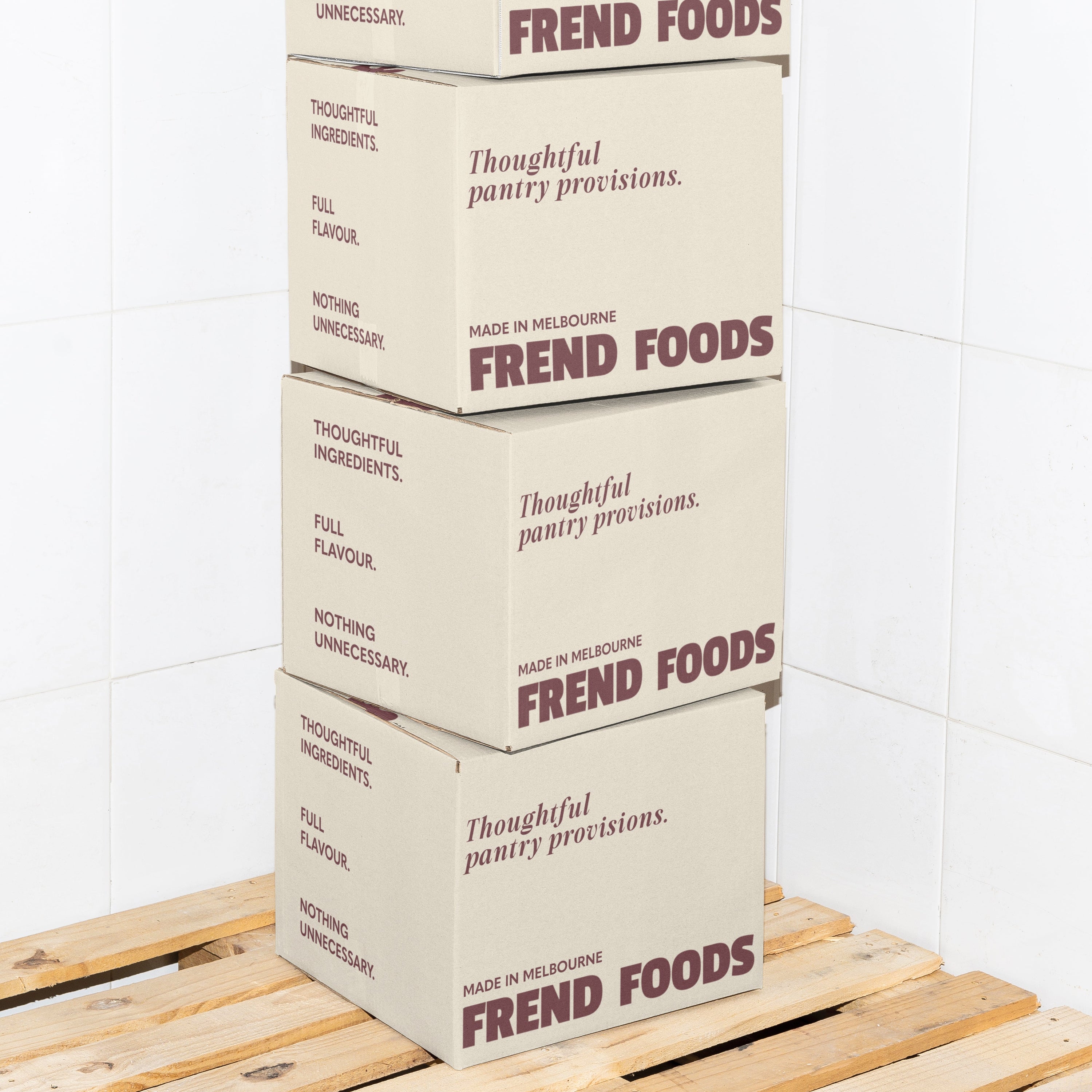 Stack of Frend Foods boxes on a wooden pallet against a white tiled wall.